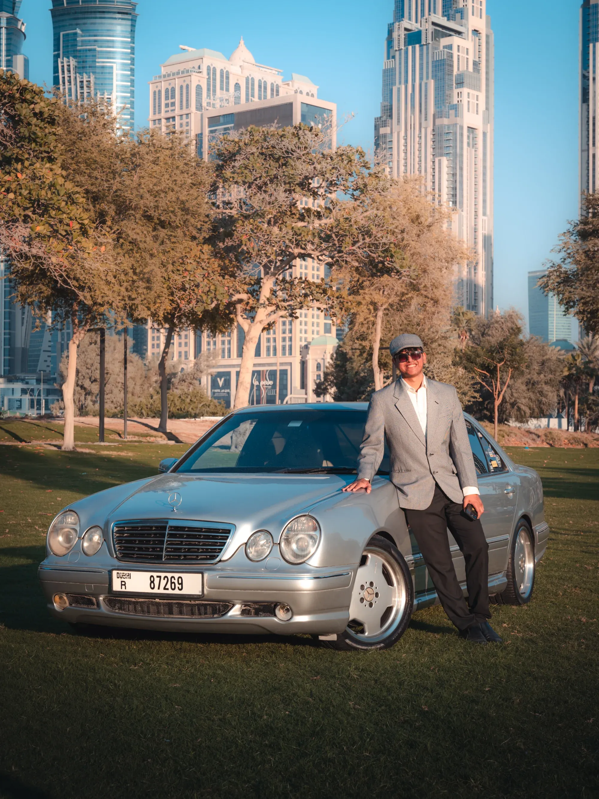 Silver Mercedes-Benz sedans on a tree-lined road, cinematic warm tones.