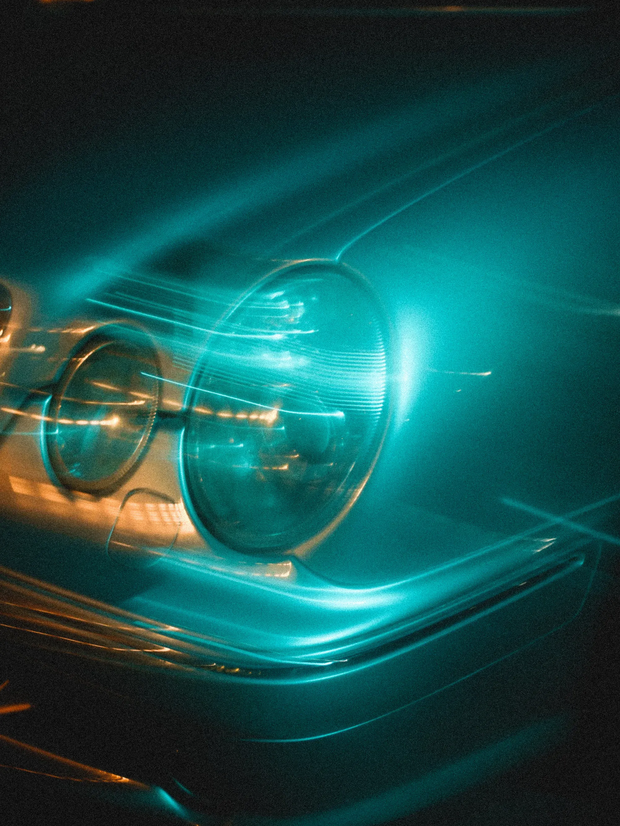 Close-up of Mercedes-Benz W210 quad headlights with teal light trails and motion blur, cinematic night mood.